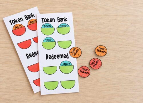 Finished screen time token charts and colorful Tech Tokens arranged on a light wood table.