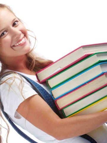Cute teenage girl holding a stack of books