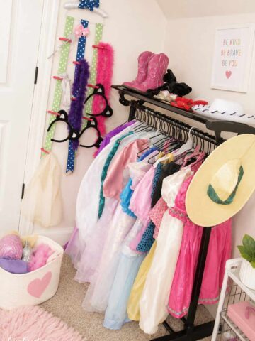 Kids’ dress-up clothes organized on a clothing rack with costumes, hats, boots, boas, and accessories.