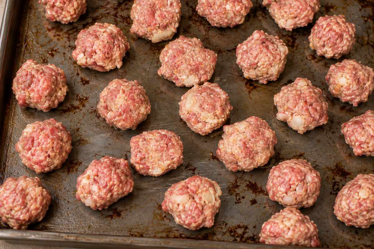 Raw homemade meatballs on a cookie sheet ready to bake