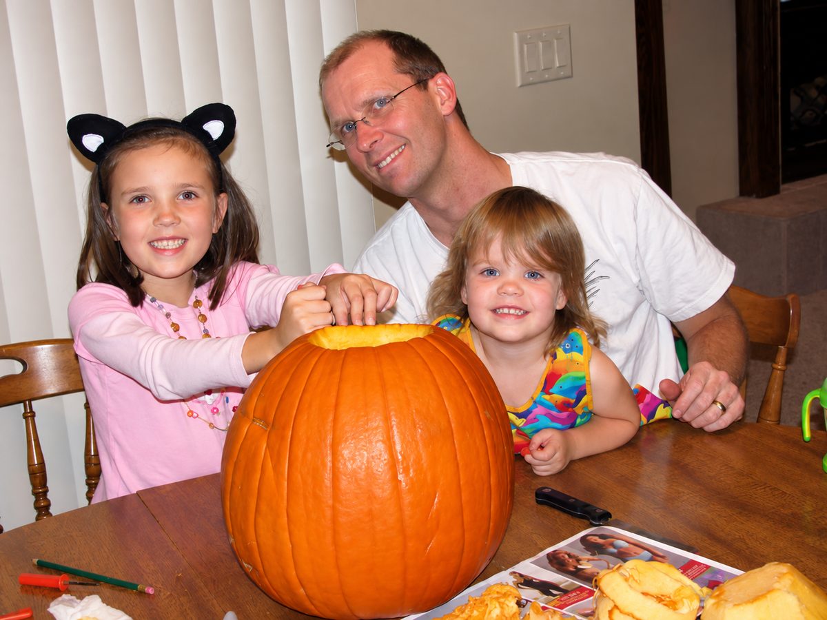 Family carving a pumpkin together for Halloween