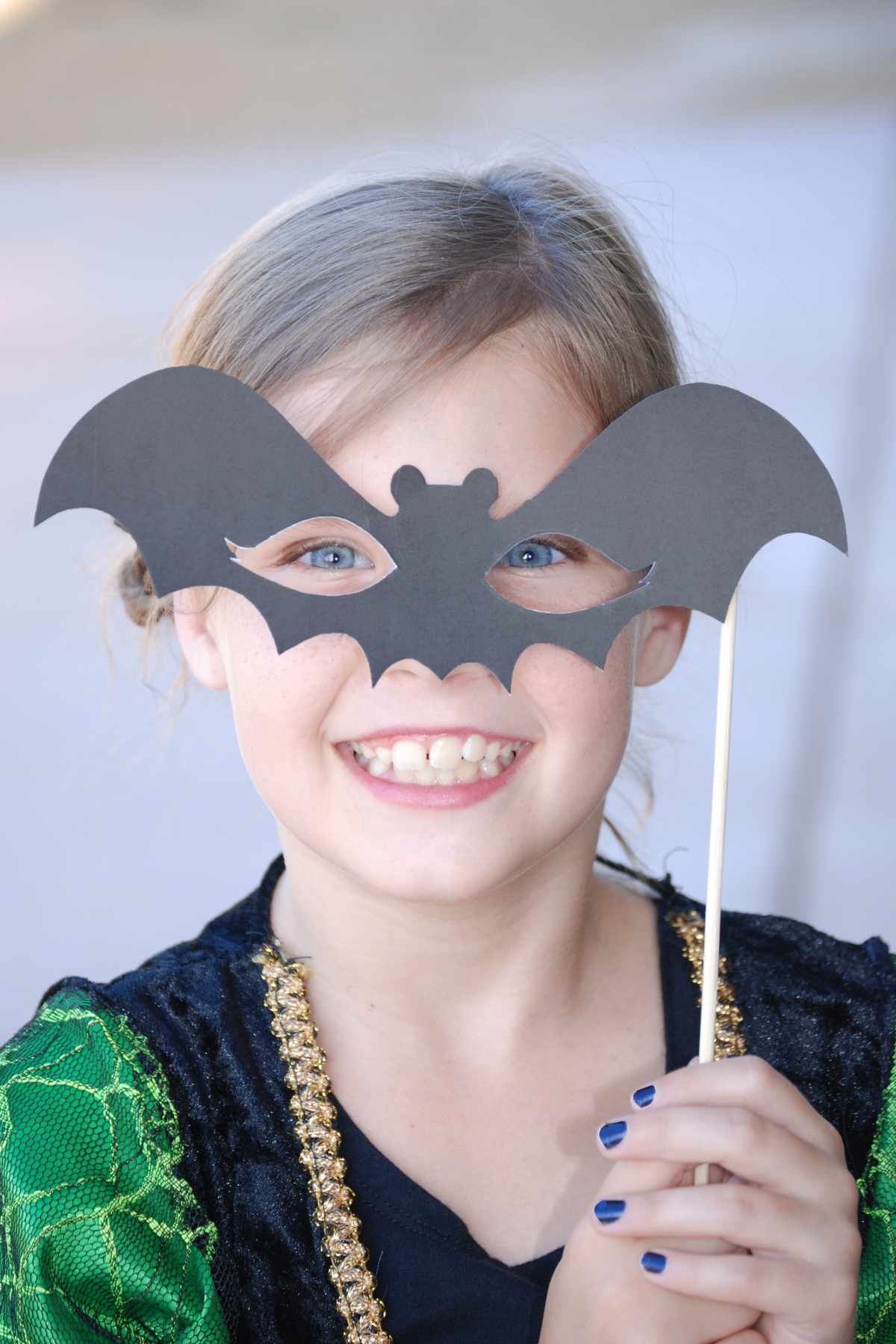 Girl holding a homemade bat mask at a Halloween class party